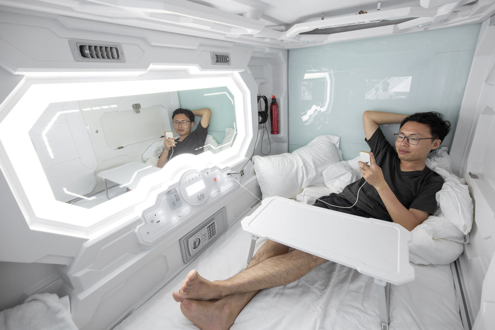 A man on a bed in a capsule hotel.