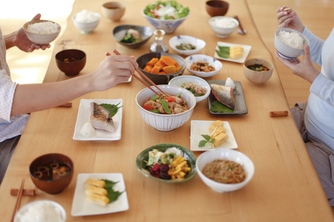 A man and woman sit opposite each other in front of a table featuring various traditional Japanese meal items