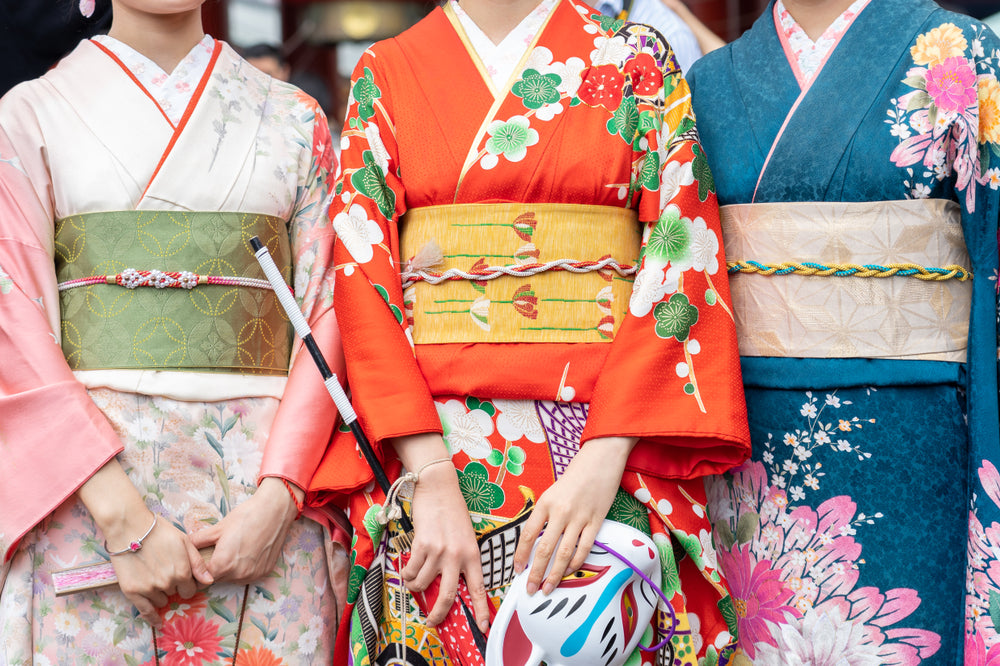 three women wearing different color kimonos.