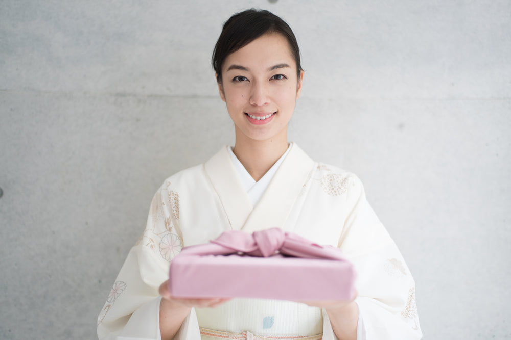 Woman giving Japanese gift wrapped in a furoshiki.